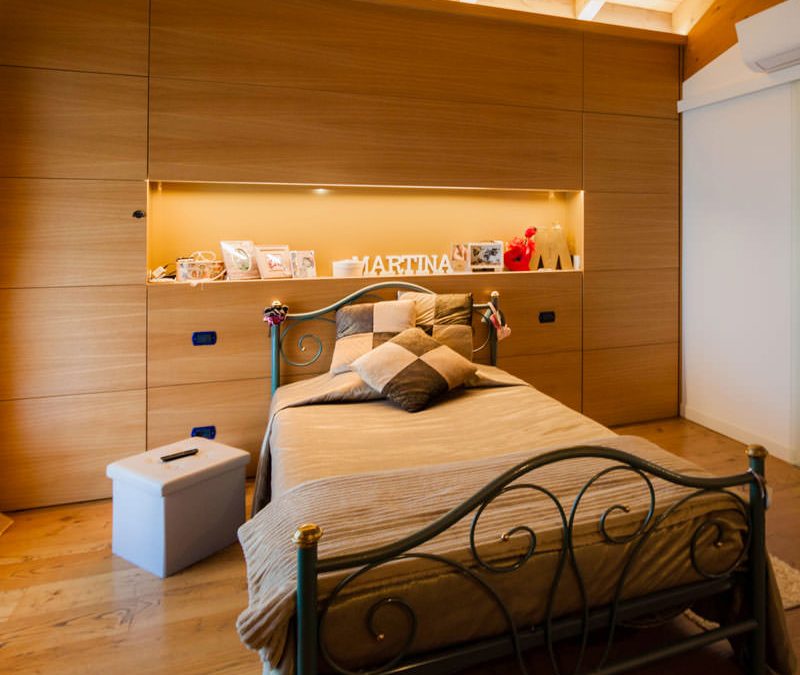 A wooden bedroom with warm natural tonalities. Functional passages and connected rooms.