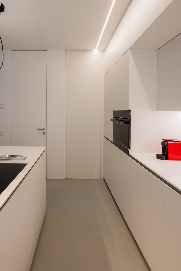 white kitchen with combined oven island hidden door laundry area